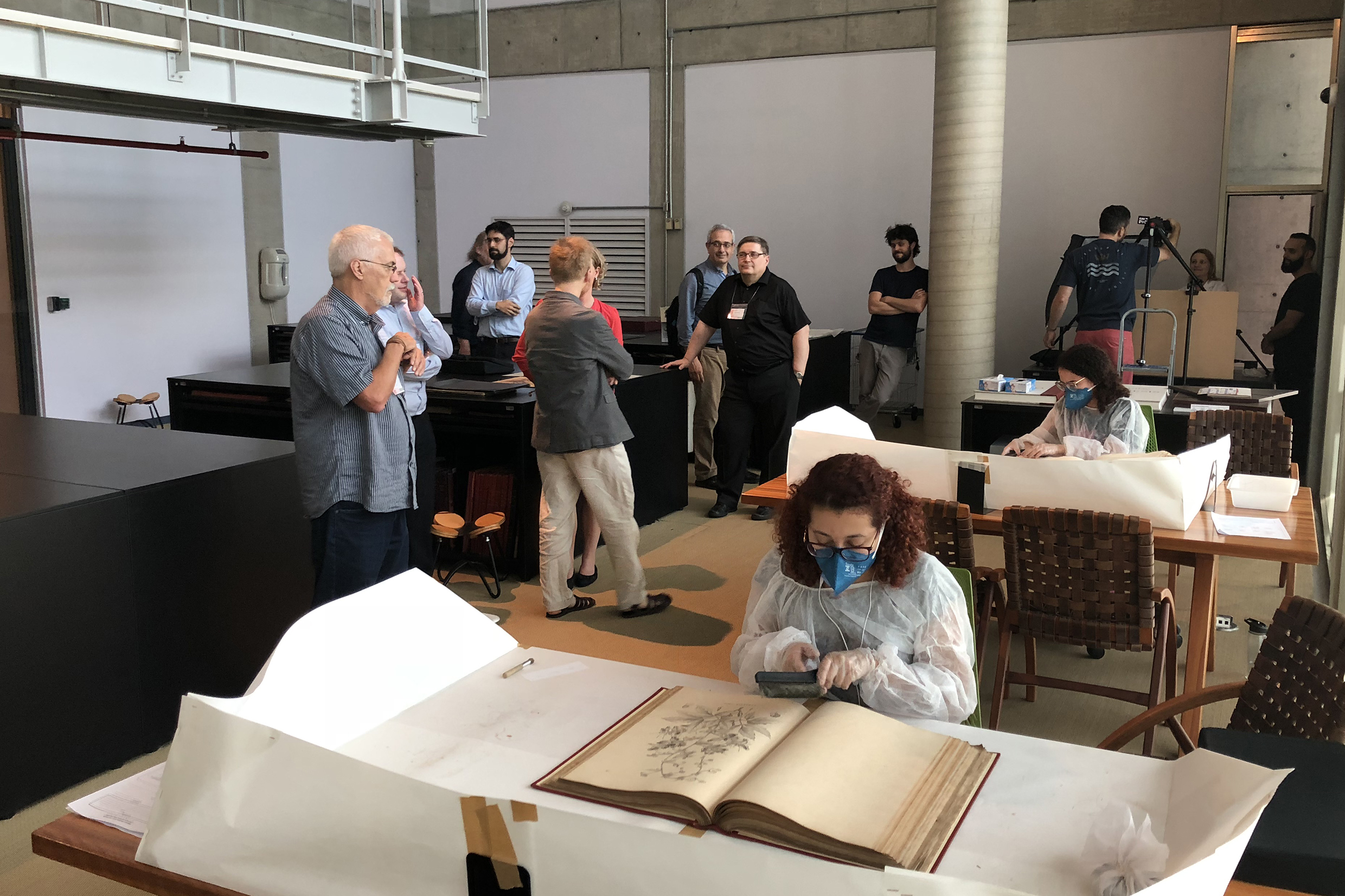 Participantes observam funcionárias da Biblioteca Brasiliana Guita e José Mindlin realizando trabalho de conservação das obras